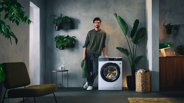 Mann steht neben Waschmaschine